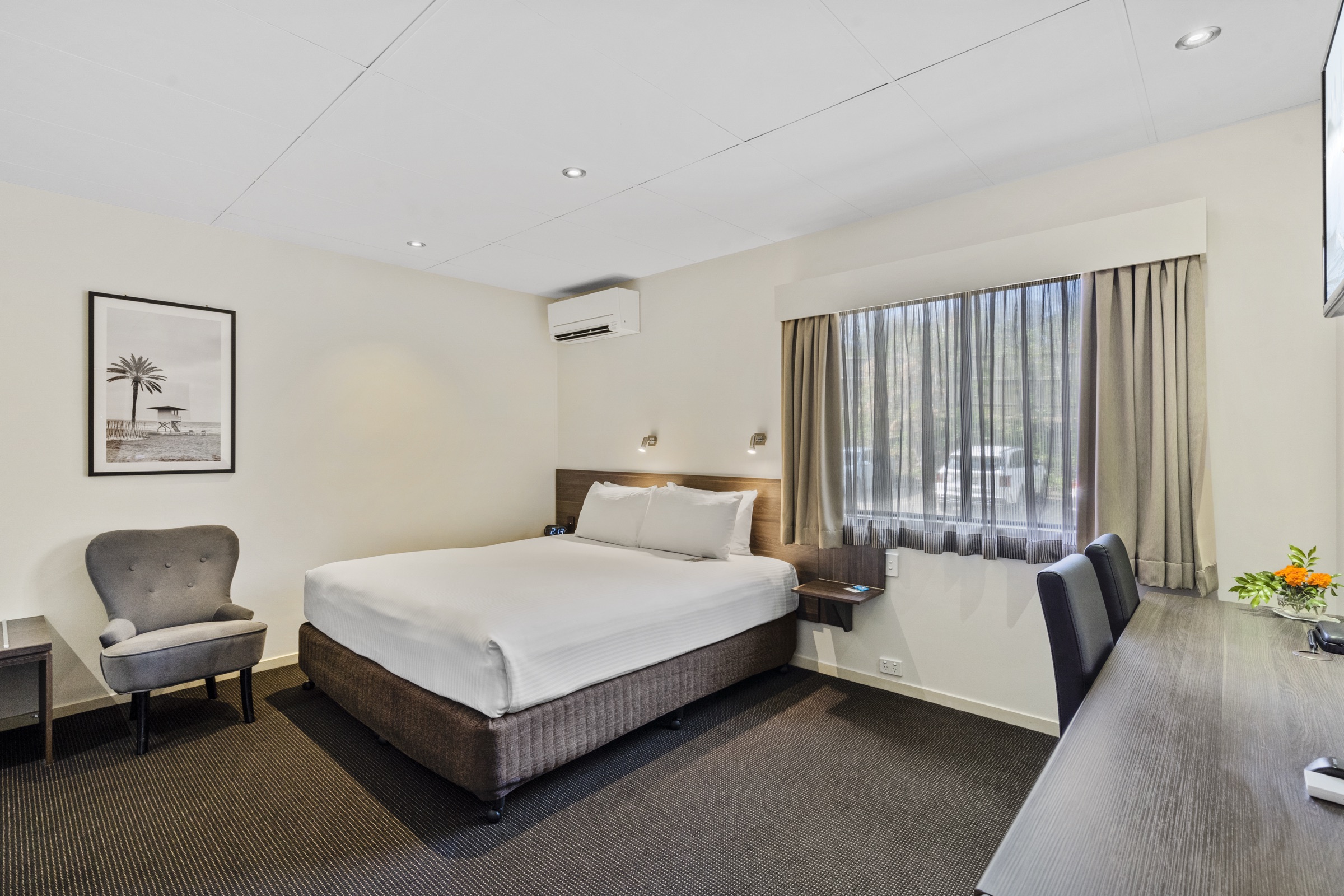 A garden-view guest room with a queen bed and lounge seating