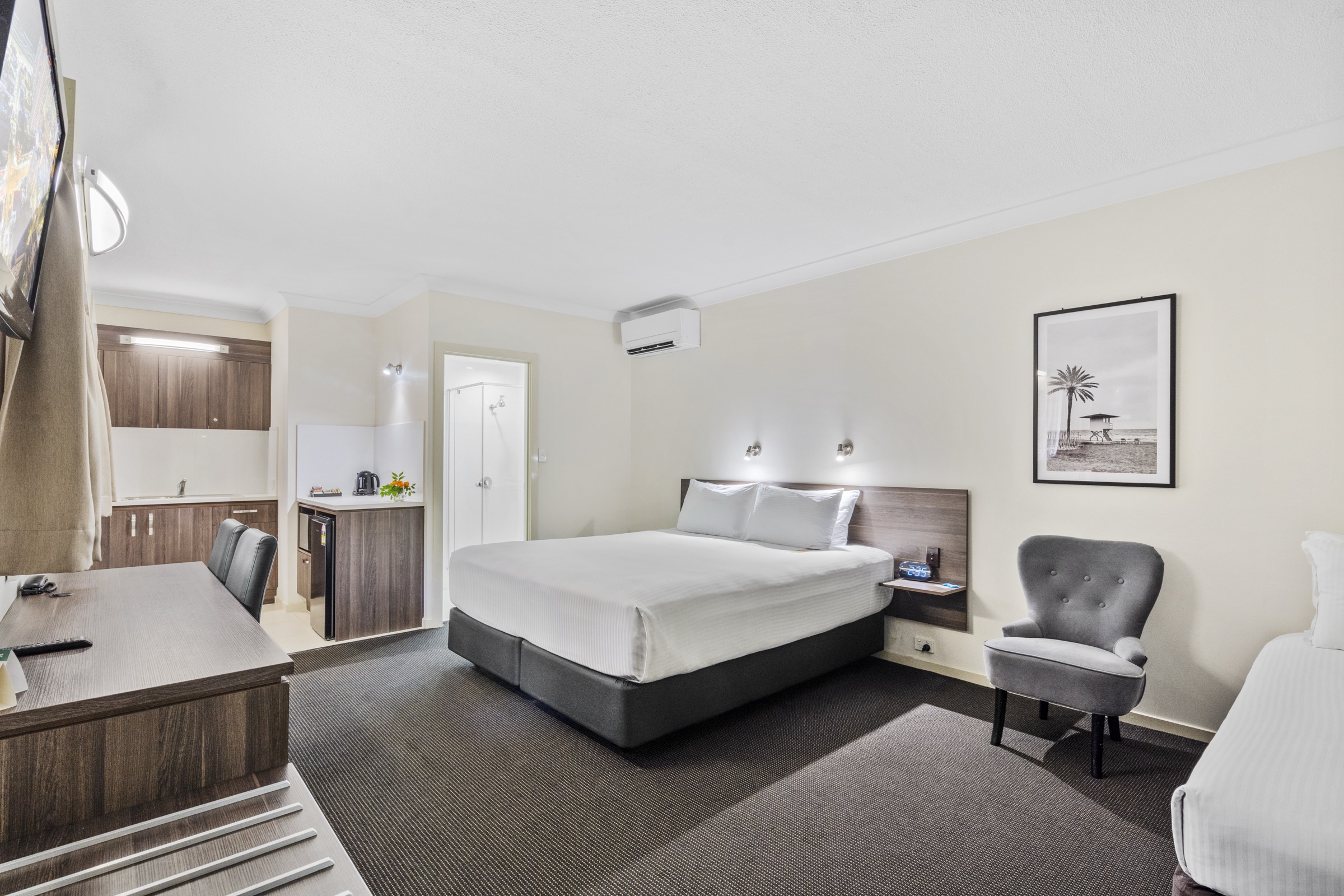 A self-contained studio with a kitchenette and lounge chair